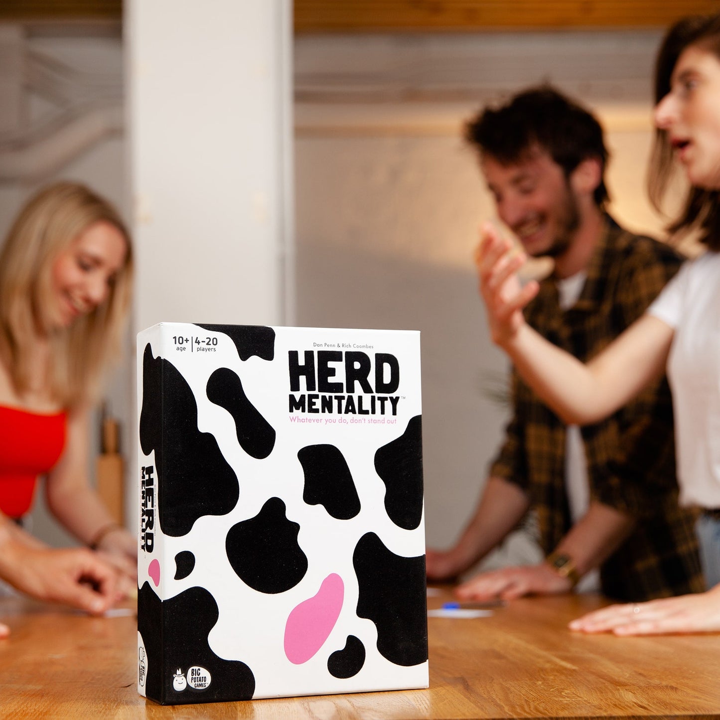 Board game box titled 'HERD MENTALITY' with people playing in the background