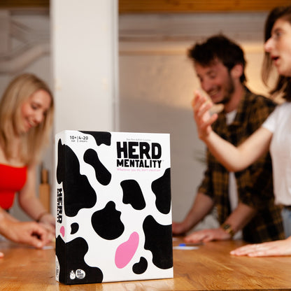 Board game box titled 'HERD MENTALITY' with people playing in the background