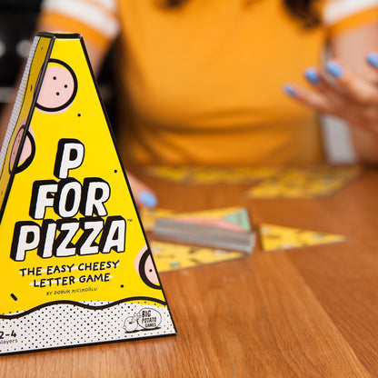 Game box for 'P for Pizza' on a table with people playing in a blurred background