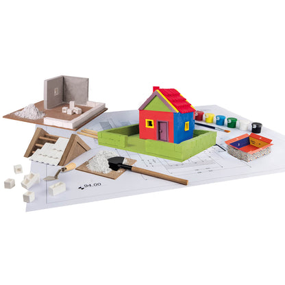 Colorful toy house set on a white surface with tools and materials.