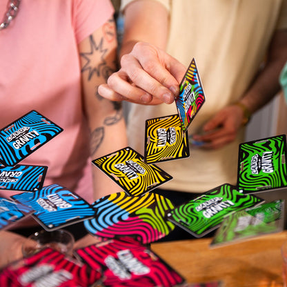 Colorful packages of a product with 'cards vs gravity' branding scattered on a surface.