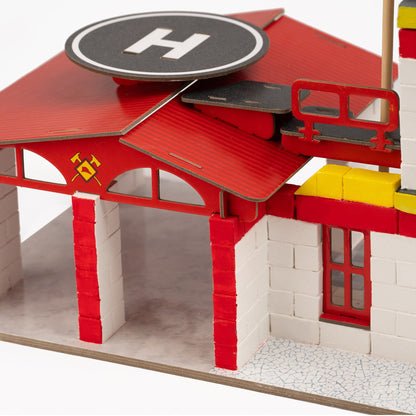 Model fire station with red roof and white walls on a white background