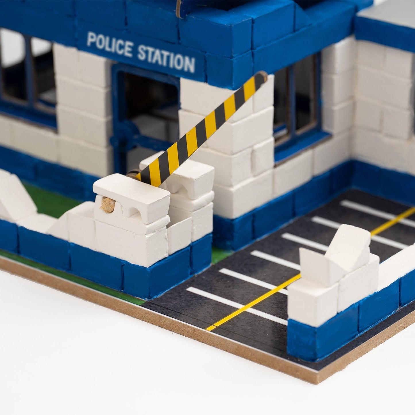 Model police station made from interlocking bricks with a barrier gate.