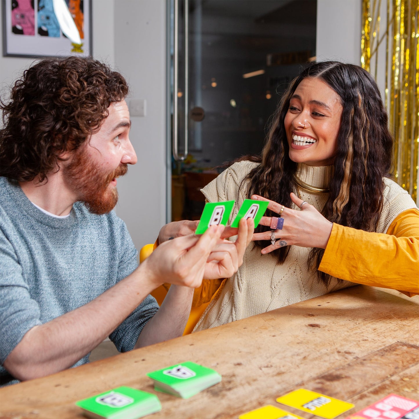 Two people playing the board game You Can't Say Umm together at a table with festive decorations in the background.