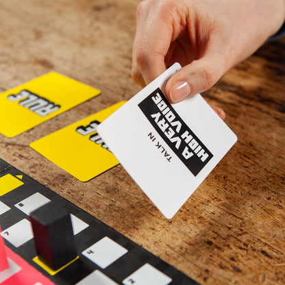 Hand holding a card with text on a wooden surface with other cards.